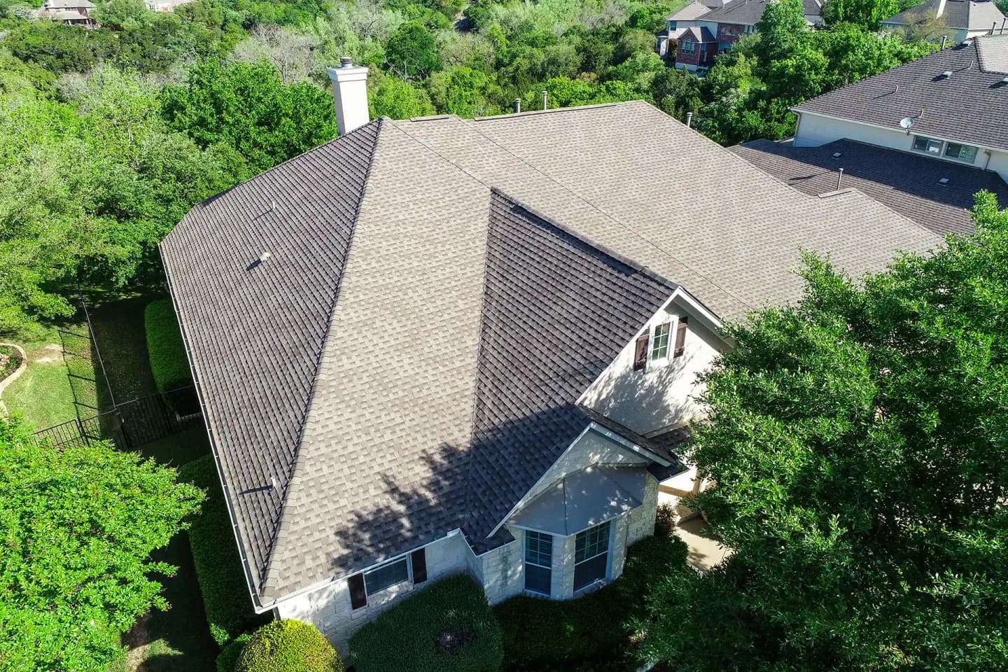 Finished shingle roof on a Texas home surrounded by trees