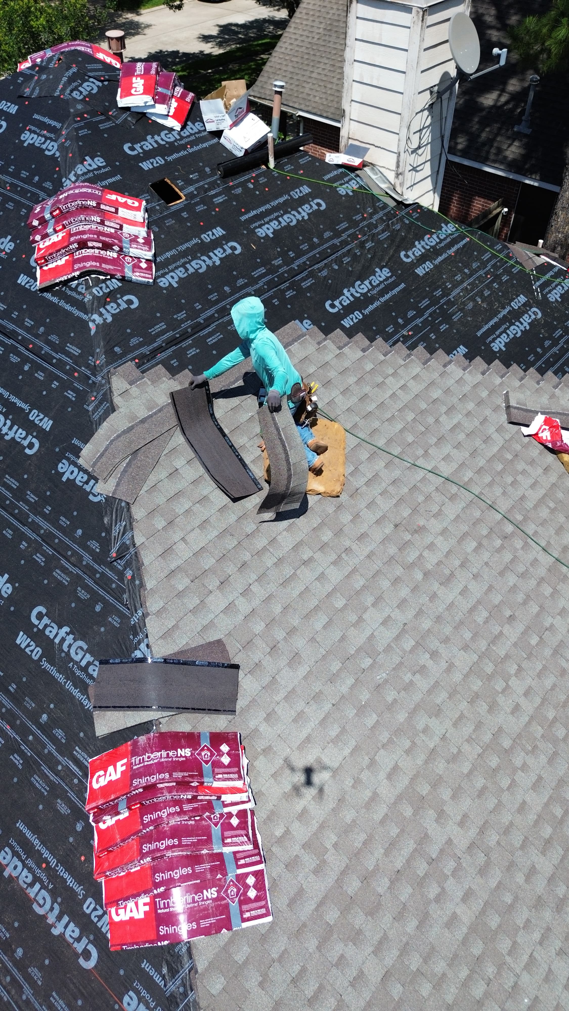 Roofing crew installing synthetic underlayment and shingles