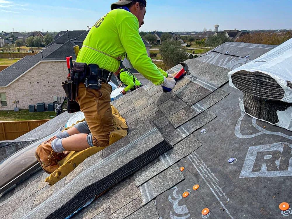 Roofer installing new asphalt shingles during a roof replacement